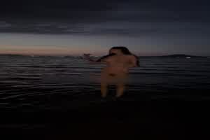 落日余晖下海中裸体的引得沙滩上赶海大哥驻足观看  背景图片